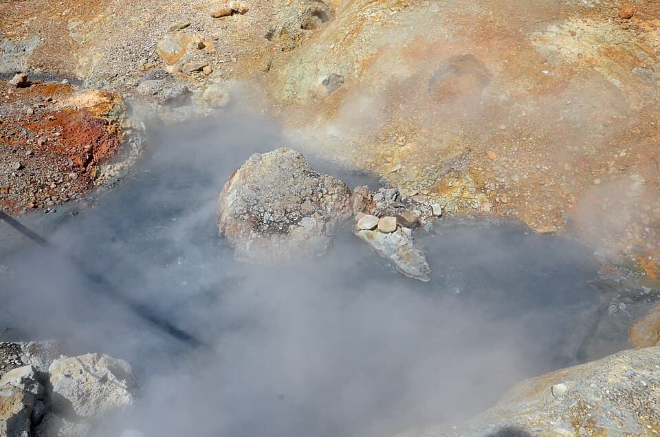 Steaming geothermal ground in Iceland with boiling water, coloured mineral crusts and unstable-looking rock