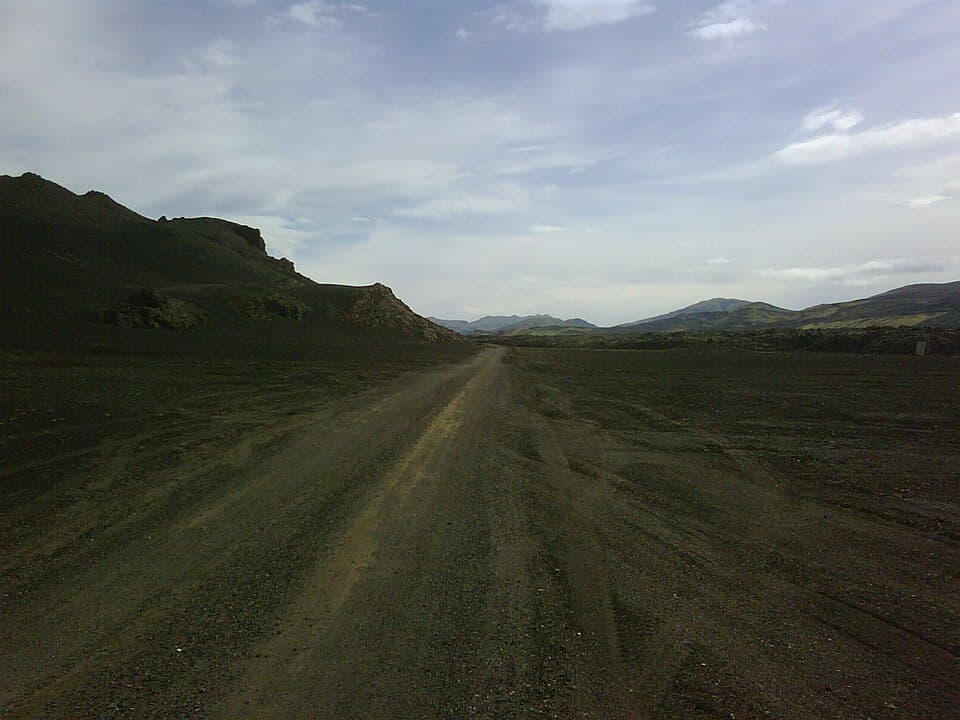 An open paved road running across Icelandic terrain under a wide sky